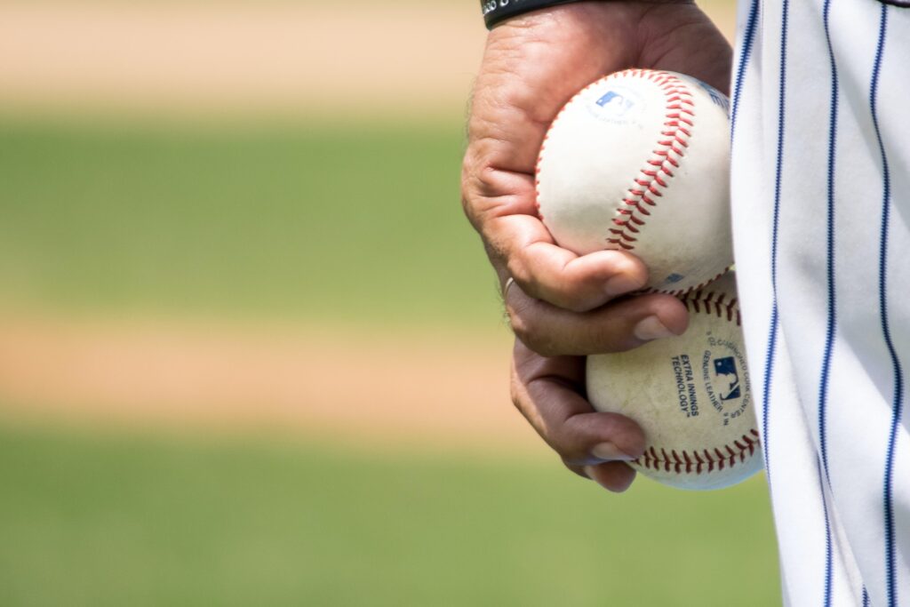 hand holding two baseballs