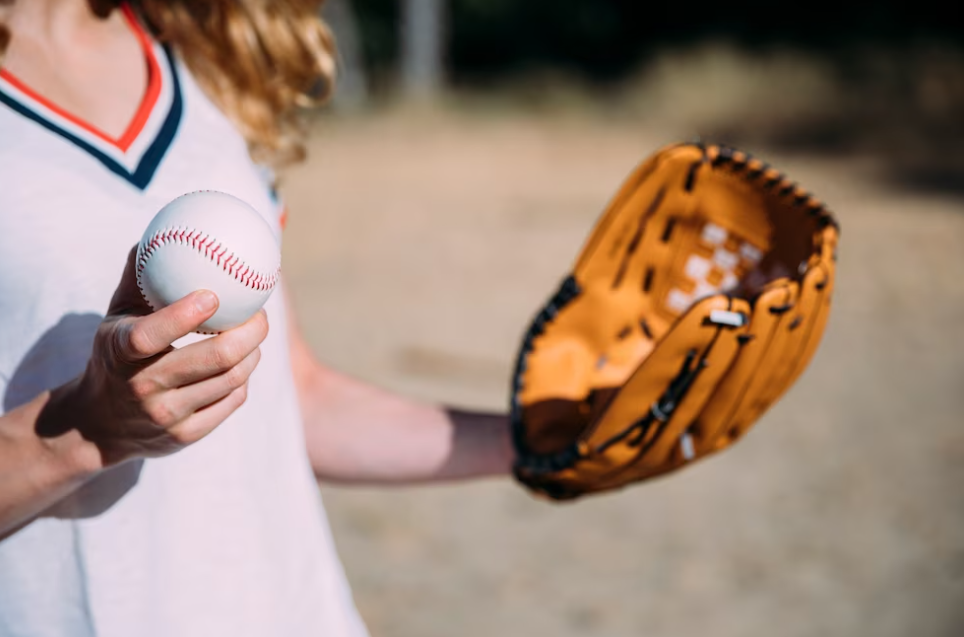 girl keeping baseball and glove on the beach